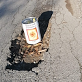 Strada della vergogna: spunta contenitore di olio per segnalare grossa buca [FOTO]